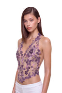 Florielle floral halter top in Aubergine, three-quarter front view showing raised hand-painted flowers, hand-beaded centers and the shaped hem.