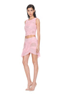 Angled front view of the light pink Marea wetlook two-piece set, showing a sleeveless draped crop top and asymmetric mini skirt.