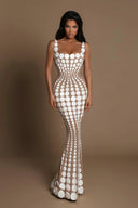 Oria White/Nude hand-painted dot gown worn by a model against a warm brown campaign backdrop.