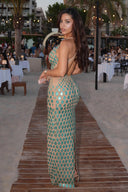 Zyra hand-painted V-neck gown in Metallic Aqua, outdoor campaign photograph showing the scale artwork and open back